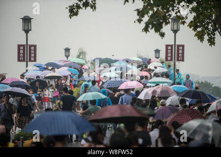 Les touristes des parasols à pied par le pont cassé sur le lac de l'Ouest dans la pluie dans la ville de Hangzhou, Zhejiang Province de Chine orientale, 4 octobre 2 Banque D'Images