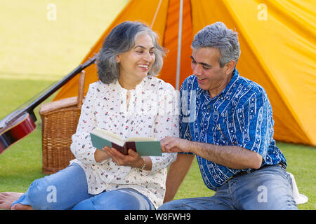 Senior couple reading book at picnic Stock Photo