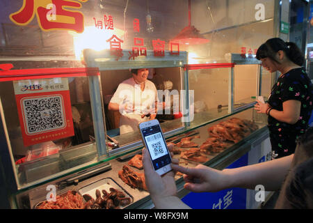 Un client chinois de scanner un QR code via le service de paiement mobile du Groupe d''Alibaba Alipay sur son smartphone, pour payer son achat à un marché libre pour nous Banque D'Images