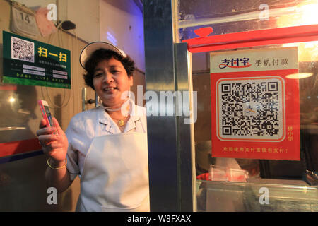 Un vendeur chinois montre son QR code pour le service de paiement mobile du Groupe d''Alibaba Alipay sur son smartphone à un marché libre dans la ville de Wenzhou, Chine de l'Est. Banque D'Images