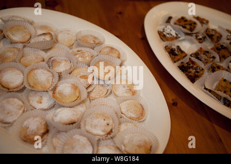 Assortiment de gâteaux saupoudrés de sucre en poudre sur un plateau, parfait pour les fêtes, les buffets et les sélections de desserts sucrés. Banque D'Images