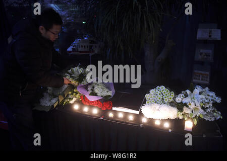 Un Chinois jette des fleurs pour les victimes du 13 novembre Paris les attaques à l'Ambassade de France à Pékin, Chine, 14 novembre 2015. Banque D'Images