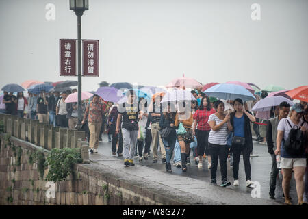 Les touristes des parasols à pied par le pont cassé sur le lac de l'Ouest dans la pluie dans la ville de Hangzhou, Zhejiang Province de Chine orientale, 4 octobre 2 Banque D'Images