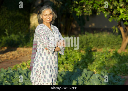 Old woman standing with her arms crossed and smiling Stock Photo