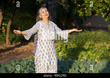 Old woman smiling avec son bras tendus Banque D'Images