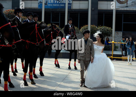 A senior couple qui sont à la fois les amoureux du cheval à pied Équitation équitation chevaux passé lors de leur cérémonie de mariage à Chongqing, Chine, le 7 mars 2015. A n Banque D'Images