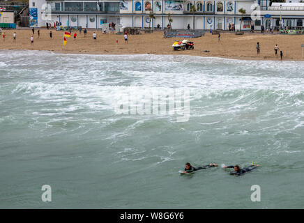 Bournemouth, Royaume-Uni. 9 Août, 2019. Les surfeurs et le personnel de la RNLI profitez au maximum de la très venteux à Bournemouth en août. Crédit : Thomas Faull/Alamy Live News Banque D'Images