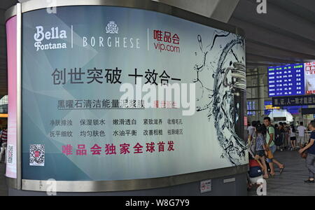 --FILE--piétons passent devant une publicité pour Bella Fontana, Borghese et détaillant de mode en ligne chinois de Vipshop vip.com Holdings Ltd. à elle Banque D'Images