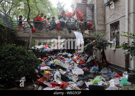 Les travailleurs chinois à l'assainissement de dissiper un tas de détritus accumulés par une personne âgée en face d'un immeuble d'appartements dans la ville de Qingdao, Chine de l'Est. Banque D'Images