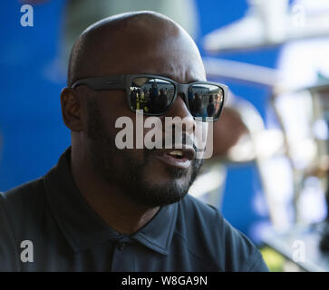 Les lunettes de soleil sont portées par la renommée de la NFL running back Marshall Faulk comme il parle aux enfants au sujet de l'exercice Banque D'Images