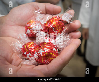 Homme tenant une poignée de Lindt Lindor bonbons emballés individuellement Banque D'Images