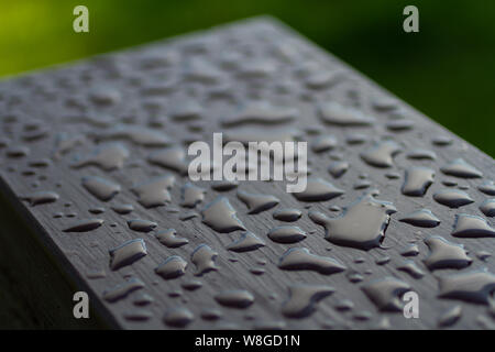 Close up de l'eau perler sur la surface d'une main courante en bois fraîchement colorées. Banque D'Images