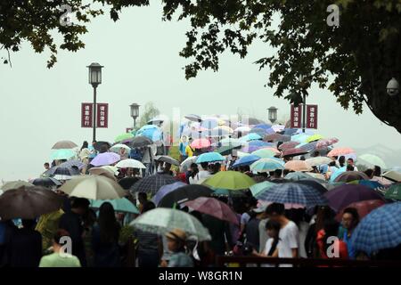 Les touristes des parasols à pied par le pont cassé sur le lac de l'Ouest dans la pluie dans la ville de Hangzhou, Zhejiang Province de Chine orientale, 4 octobre 2 Banque D'Images