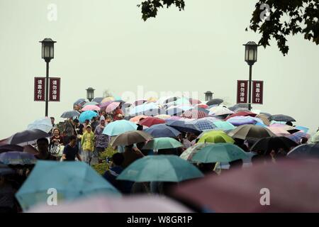 Les touristes des parasols à pied par le pont cassé sur le lac de l'Ouest dans la pluie dans la ville de Hangzhou, Zhejiang Province de Chine orientale, 4 octobre 2 Banque D'Images