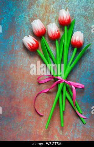 Tulipes artificielles, un bouquet de fleurs de tulipes en bois sur un fond bleu. Couleur blanc rouge tête de tulipe Banque D'Images