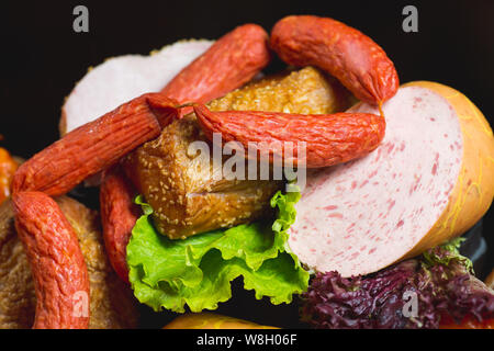 Différents types de saucisses et produits de viande sur un fond noir. Banque D'Images