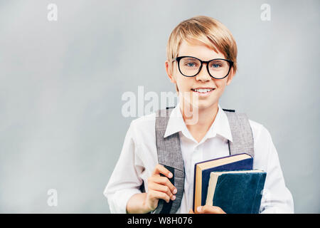 Cheerful élève en verres portant des livres et d'un cartable Banque D'Images