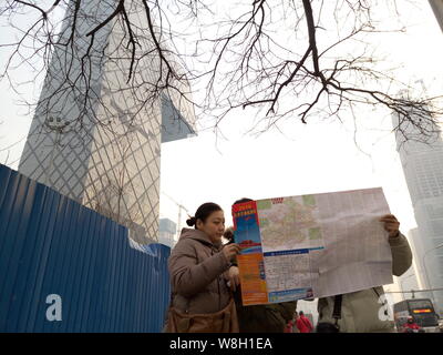 --FILE--touristes d'examiner une carte près de la CCTV Tower, le siège de la télévision centrale de Chine, dans le smog lourde à Beijing, Chine, 19 décembre 2015. Banque D'Images