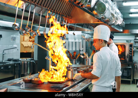 Cuisine moderne. Les cuisiniers préparent les repas sur la cuisinière dans la cuisine du restaurant ou hôtel. L'incendie dans la cuisine. Banque D'Images