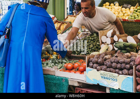 Londres, Royaume-Uni - 16 juillet 2019 : femme achète les fruits et légumes frais à partir d'un stand au marché de Brixton, un marché communautaire géré par des négociants locaux à t Banque D'Images