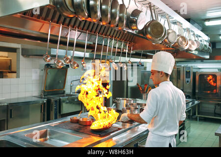 Cuisine moderne. Les cuisiniers préparent les repas sur la cuisinière dans la cuisine du restaurant ou hôtel. L'incendie dans la cuisine. Banque D'Images