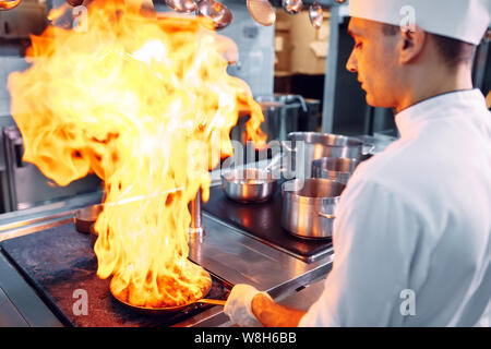 Cuisine moderne. Les cuisiniers préparent les repas sur la cuisinière dans la cuisine du restaurant ou hôtel. L'incendie dans la cuisine. Banque D'Images