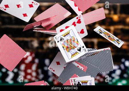 Le rouge et le bleu soutenu en cascade les cartes à jouer devant un fond d'empiler des jetons de poker . La profondeur de champ est tellement de cartes sont au point et Banque D'Images