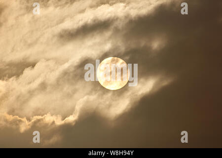 Le disque du soleil brille à travers les nuages et le brouillard. Banque D'Images