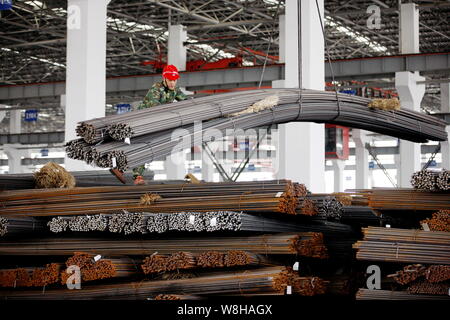 --FILE--Un travailleur chinois dirige une grue pour soulever les barres d'armature en acier à l'entrepôt d'une usine sidérurgique de Huaibei ville, province d'Anhui en Chine orientale Banque D'Images