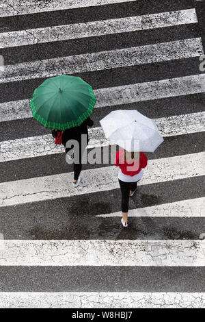 Scène de deux femmes avec parapluie mode traversant le trottoir. Vue d'en haut. Rainy day concept Banque D'Images