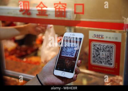 Un client chinois de scanner un QR code via le service de paiement mobile du Groupe d''Alibaba Alipay sur son smartphone, pour payer son achat à un marché libre pour nous Banque D'Images