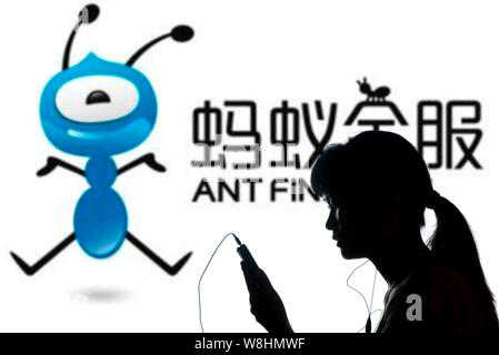 --FILE--un piéton utilise son téléphone mobile devant une publicité pour Ant Financial Services, une filiale du géant de l'e-commerce chinois Alibaba G Banque D'Images