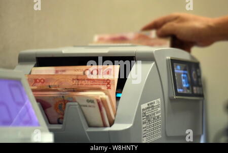 --FILE--un greffier chinois utilise une machine de comptage de caisse à compter de RMB (renminbi) yuan billets à une succursale de la Banque agricole de Chine (ABC) dans Qiongha Banque D'Images