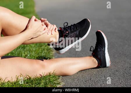 Femme portant des formateurs holding sa cheville. Banque D'Images