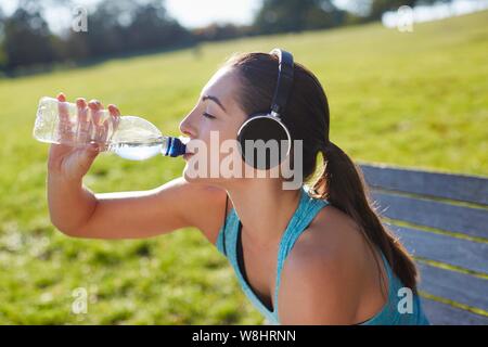 Jeune femme portant des écouteurs de l'eau potable. Banque D'Images