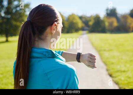 Jeune femme portant des vêtements de sport contrôle de sa montre. Banque D'Images