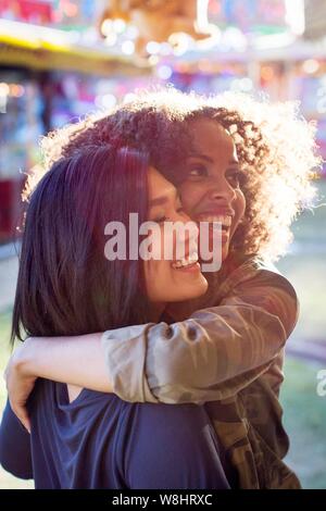 Deux jeunes femmes s'étreignant et rire dans la lumière du soleil. Banque D'Images