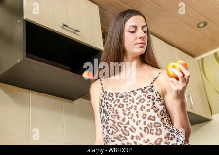 Belle femme manger un big red apple, vue de dessous Banque D'Images