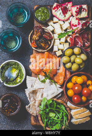 L'antipasto. Set de vin apéritif. Jambon Serrano, saumon fumé, tomates séchées et fromage frais d'olive, du vin à bord. Vue de dessus, l'arrière-plan gris cncrete. Banque D'Images