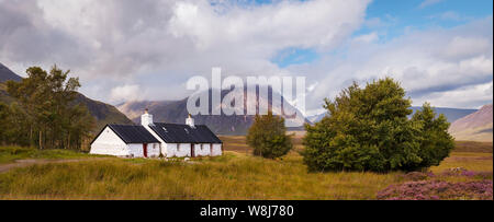 Vue imprenable de Black Rock Cottage dans les highlands écossais, en vue de Buachaille Etive Mòr sur une journée ensoleillée, avec des nuages sur la montagne. Banque D'Images