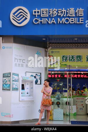 --FILE--un piéton parle sur son téléphone portable à côté d'une publicité pour les réseaux 4G LTE de China Mobile à Chongqing, Chine, le 28 juin 2013. Ch Banque D'Images