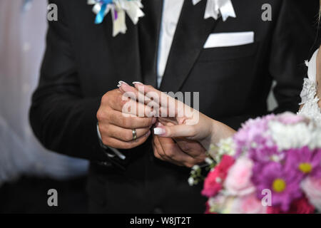 Close up de la part de la mariée met un anneau de mariage sur le doigt de mariés. Les mains de l'époux et l'épouse, c'est portant un anneau sur le doigt sur le jour de Banque D'Images