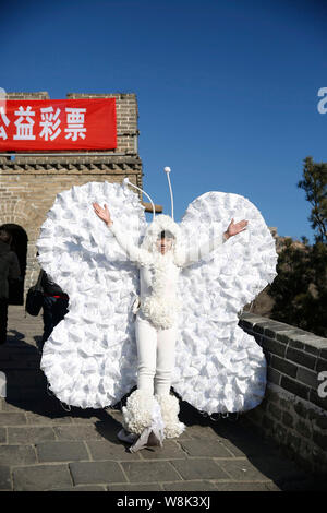 L'artiste chinois Kong Ning, droit, vêtu d'un costume de papillon fait avec 365 masque de visage pose à la Grande Muraille de Badaling, à la périphérie de Beijing, Banque D'Images