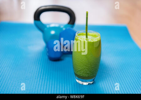 La perte de poids saine alimentation green smoothie de légumes avec haltères kettlebells et tapis d'exercice dans la salle de sport. Concept de santé et de remise en forme. Régime Végétarien et la nutrition pour la formation de force. Banque D'Images