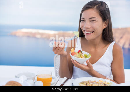 Alimentation saine. Belle femme mangeant bol de salade de fruits au petit-déjeuner à une terrasse. Jeune femme est d'avoir un petit-déjeuner sain à l'extérieur. Banque D'Images