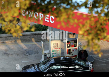 --FILE--un pilote chinois ravitaille sa voiture dans une station de Sinopec dans la ville de Qingdao, province du Shandong en Chine de l'Est, 3 novembre 2015. Chine Petroleu Banque D'Images