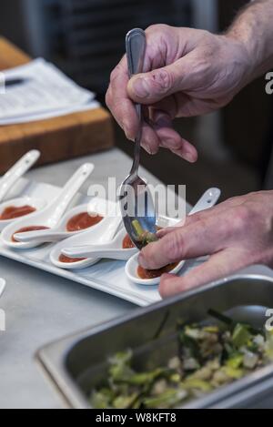 Photo verticale de la main d'une personne avec une cuillère à mettre ketchup en grandes cuillères blanches Banque D'Images