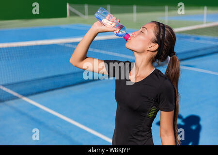 Joueur de tennis saine soif désaltérante de boire santé sport boire de l'eau bouteille plastique hydratant avant de jouer à un jeu sur bleu hardcourt. Athlète professionnel vivant une vie active mettre en place. Banque D'Images