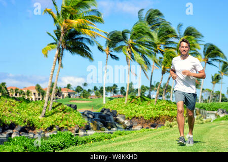 Mode de vie actif homme runner jogging en fin haut quartier résidentiel de luxe tropical américain - Miami Floride vivant. En cours de remise en forme de sexe masculin en bonne santé de l'athlète sur l'herbe cardio en été. Banque D'Images