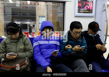 --FILE--Chinese passagers utilisent leurs smartphones pour surfer sur Internet sur une rame de métro à Beijing, Chine, 14 décembre 2015. Pour la première fois, mor Banque D'Images